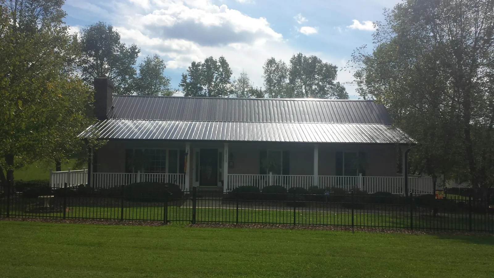 Gray metal roof on a brick ranch with a full width front porch — Gutter Guard Installation work by our crew in Jackson